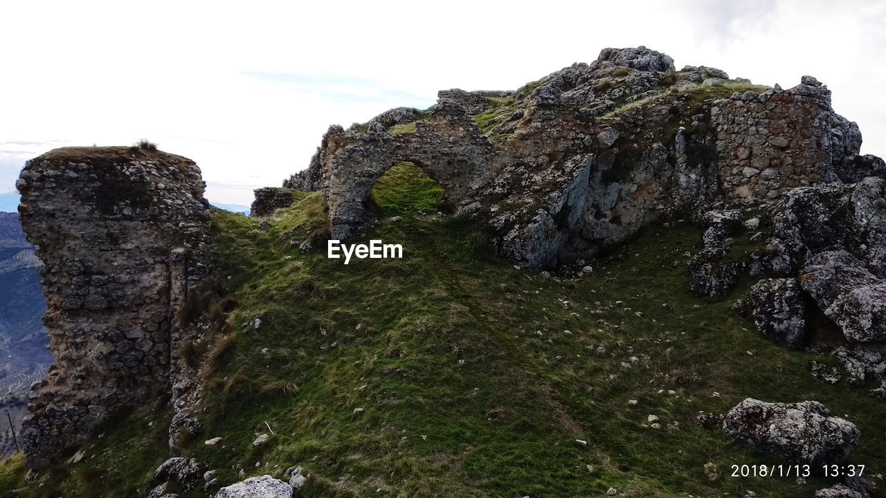 LOW ANGLE VIEW OF ROCK FORMATION BY MOUNTAIN AGAINST SKY