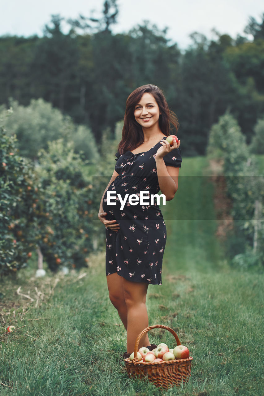 PORTRAIT OF YOUNG WOMAN STANDING ON FIELD