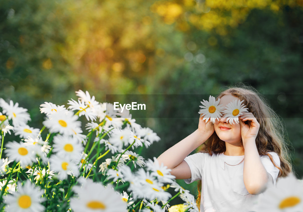 Child with daisy eyes on green background in a summer park. healthy lifestyle concept.