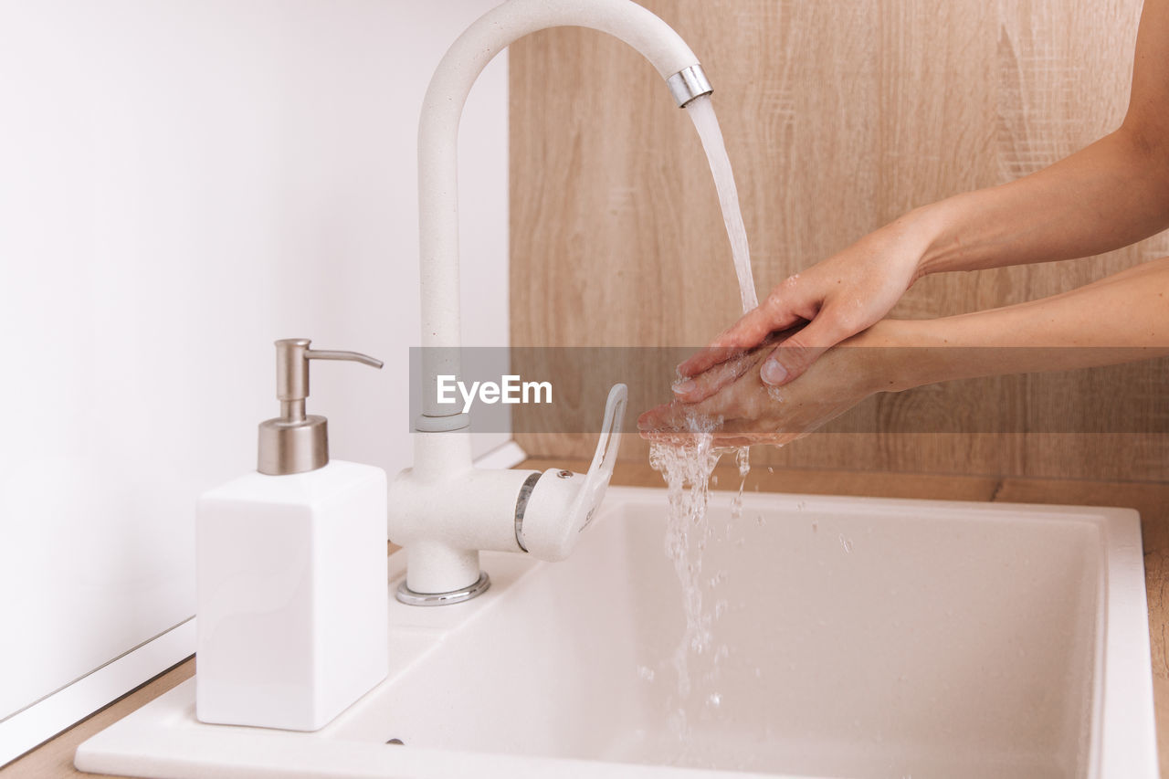 cropped hands washing faucet in sink