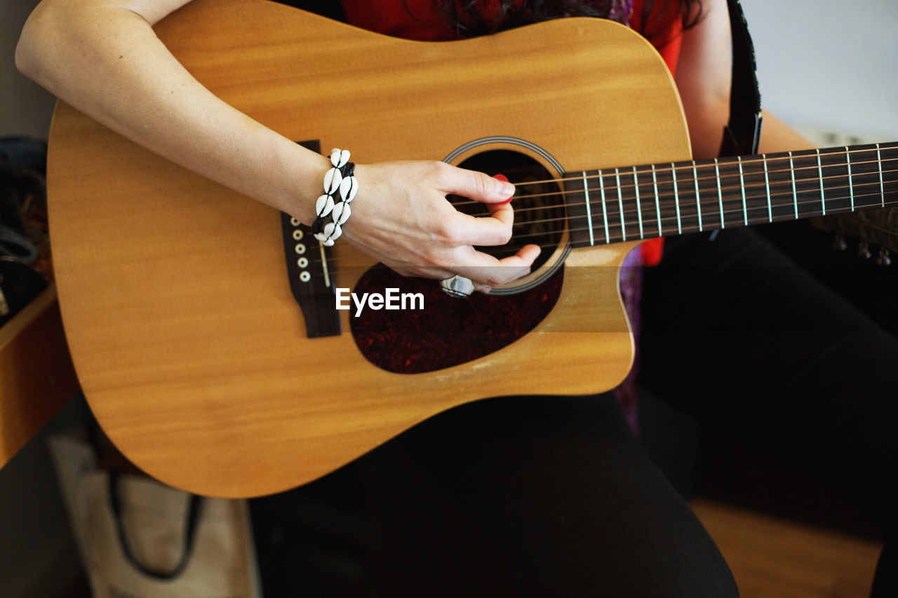 Young woman playing acoustic guitar at a recording studio