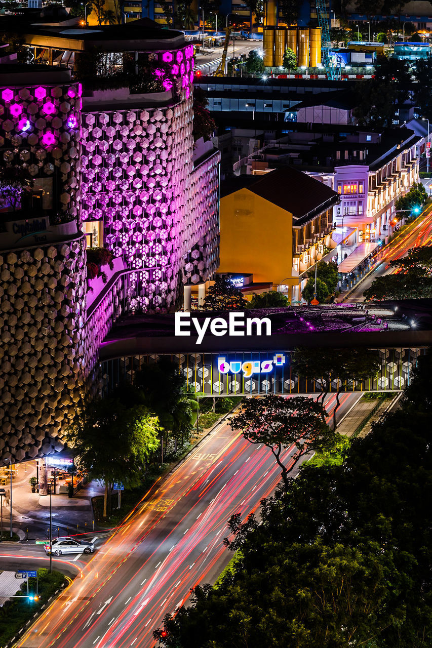 High angle view of light trails on road amidst buildings at night