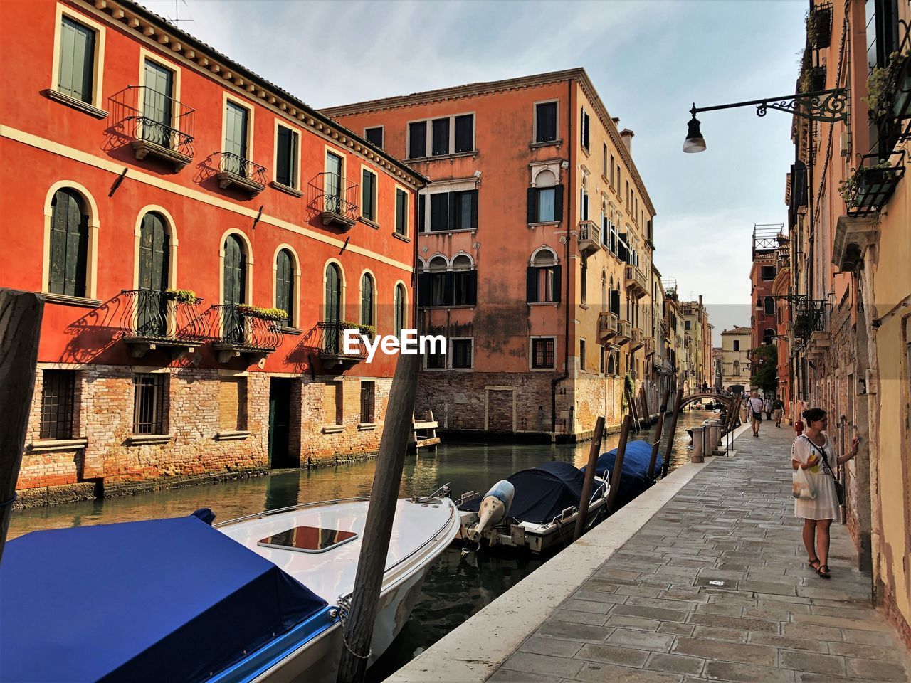 PEOPLE ON CANAL AMIDST BUILDINGS IN CITY