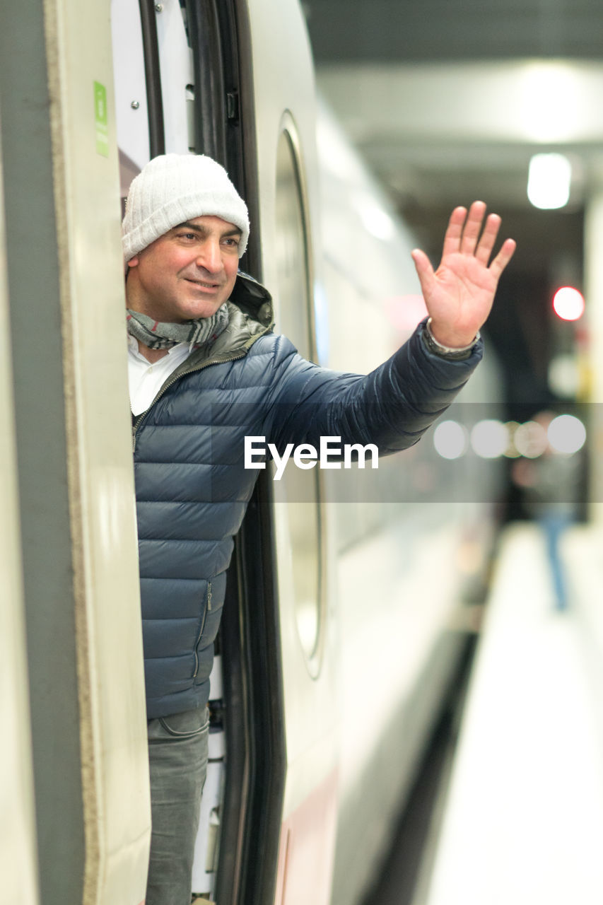 Man waving hand while standing in train