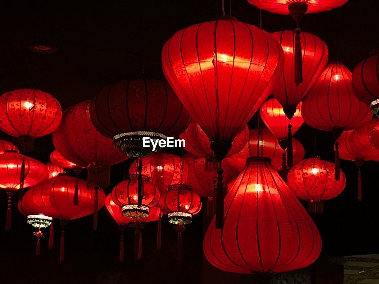 LOW ANGLE VIEW OF ILLUMINATED LANTERNS HANGING IN NIGHT