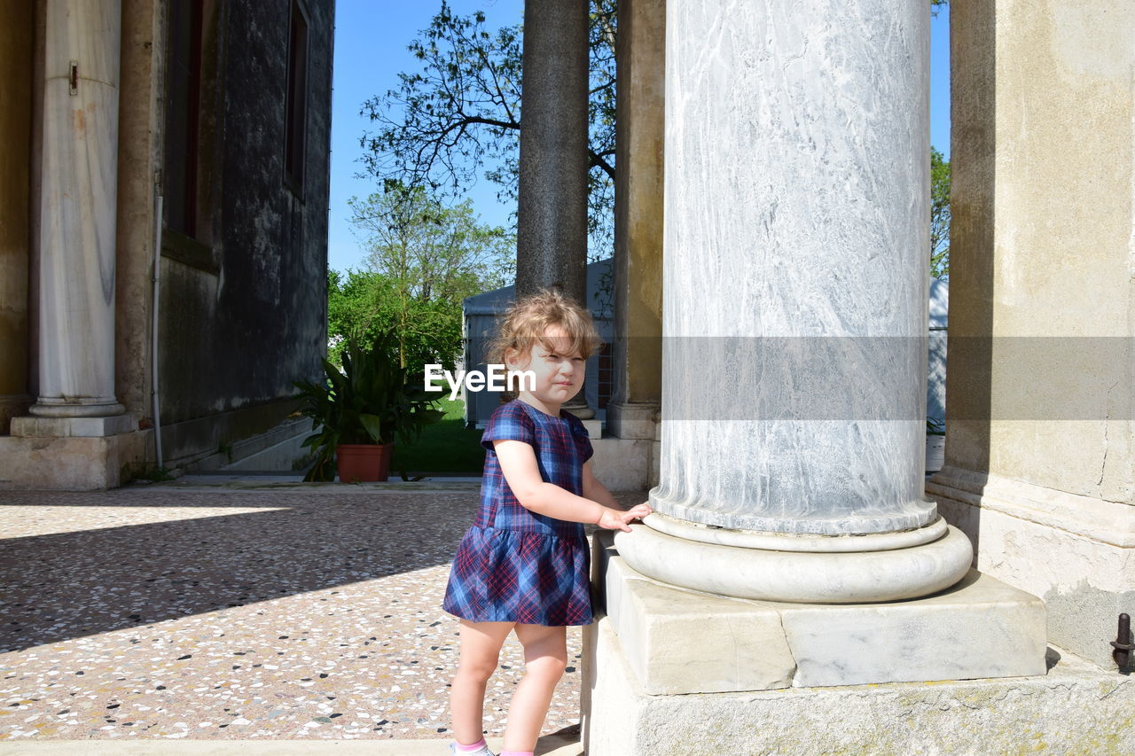 Cute girl standing by column in city