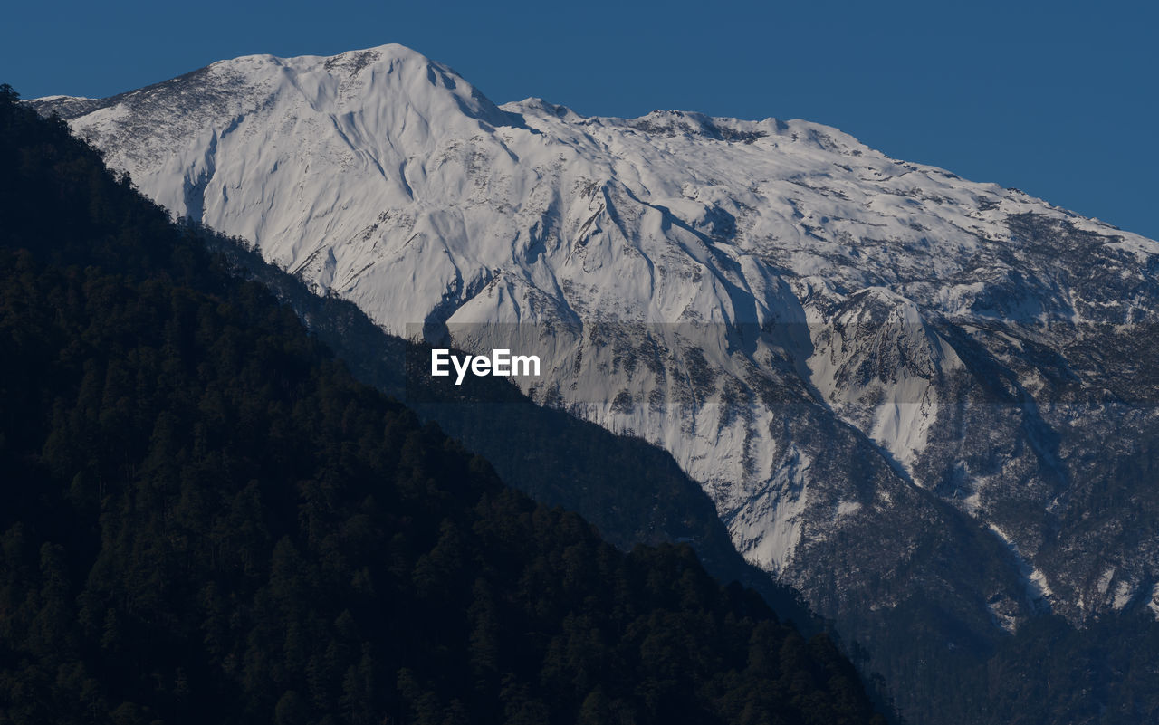 mountain, scenics - nature, mountain range, beauty in nature, snow, environment, cold temperature, sky, winter, landscape, nature, ridge, snowcapped mountain, summit, no people, mountain peak, tranquility, travel destinations, tranquil scene, land, non-urban scene, clear sky, outdoors, pinaceae, day, coniferous tree, blue, travel, wilderness, pine tree, tree, plateau, extreme terrain, tourism, plant, massif, idyllic