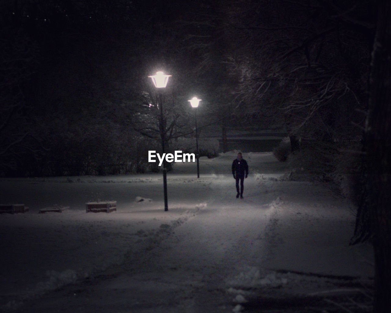 REAR VIEW OF PERSON WALKING ON SNOW COVERED FIELD AT NIGHT