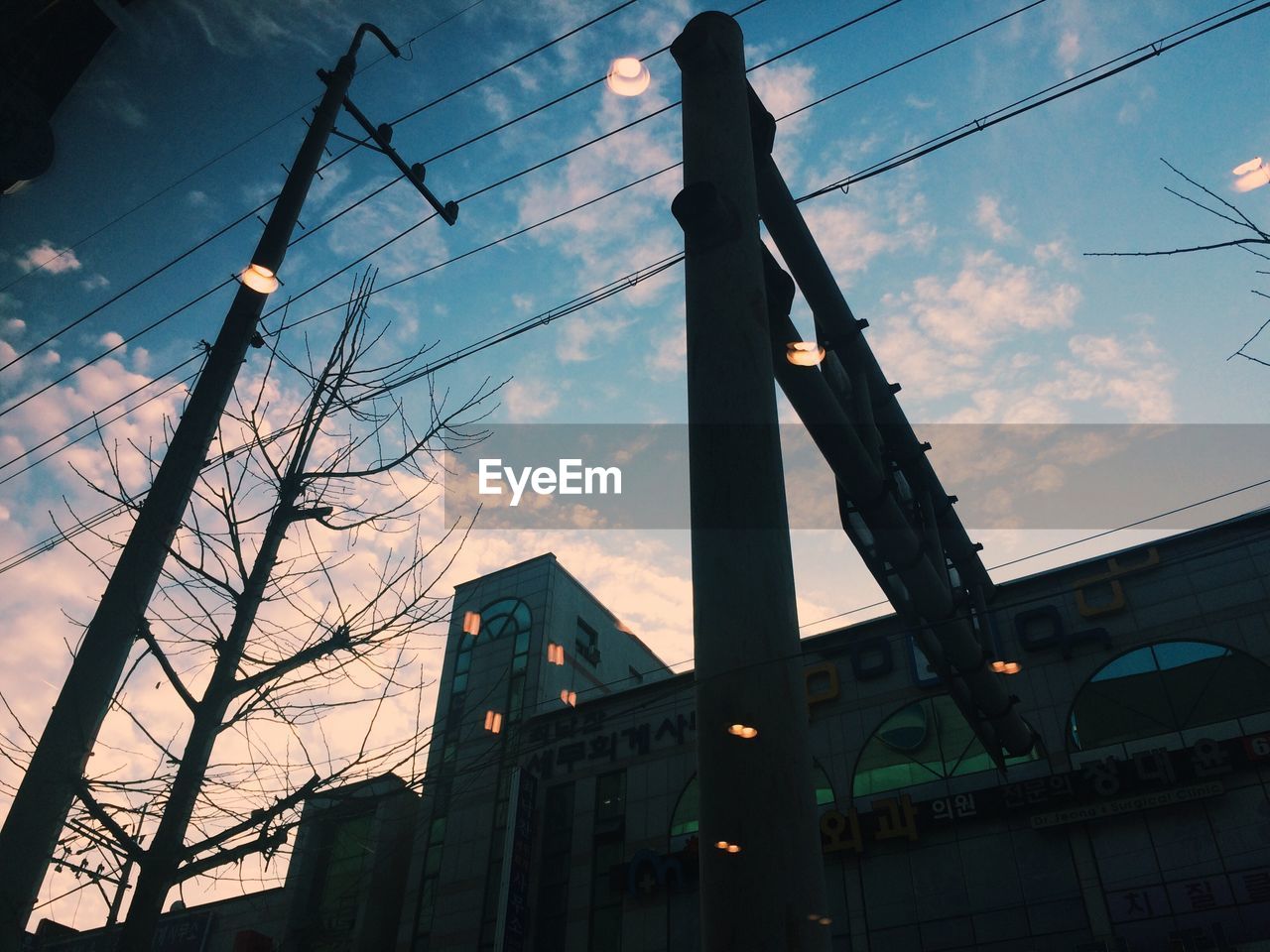 Low angle view of electricity pylon against cloudy sky