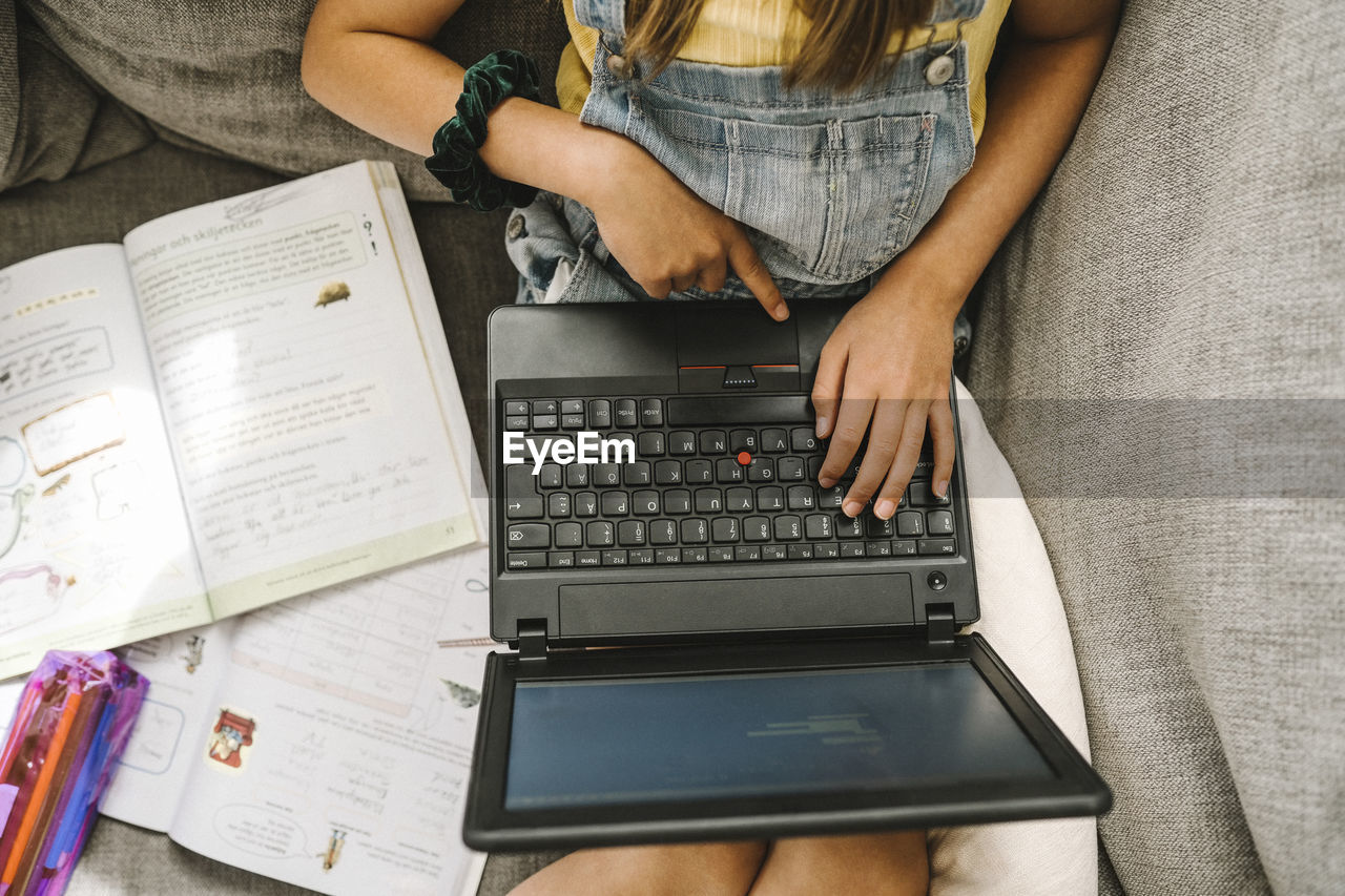 Girl learning online through laptop at home