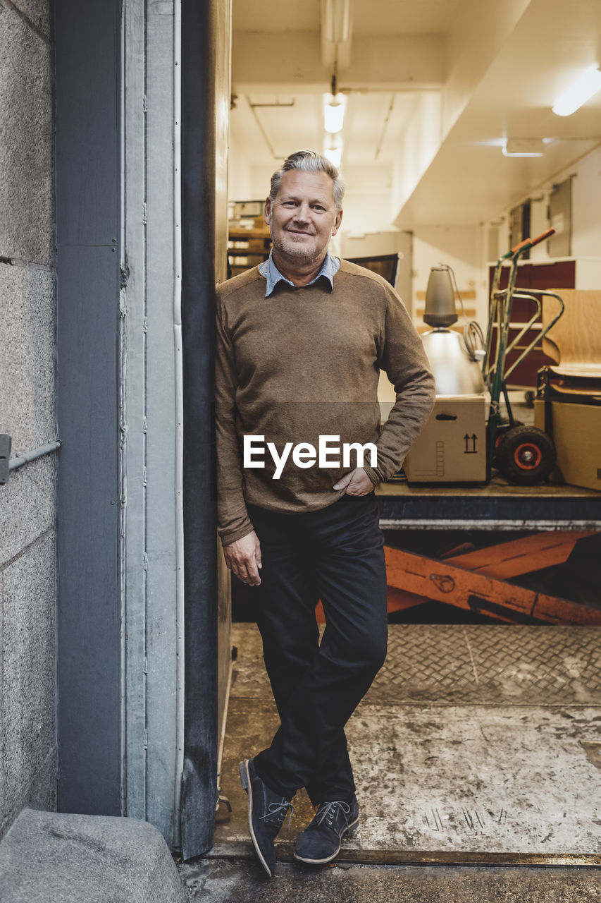 Full length portrait of mature businessman standing in new office