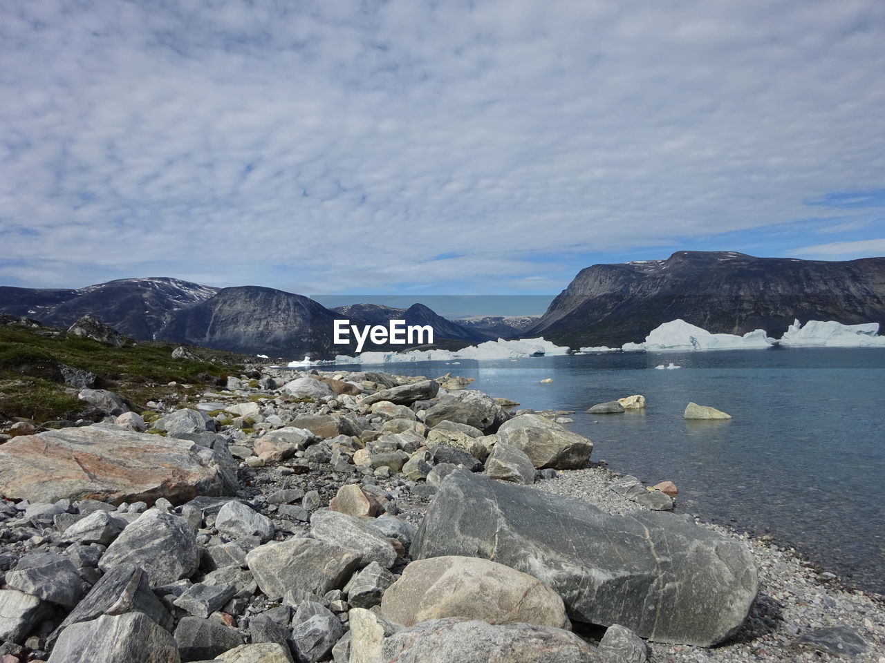 Scenic view of sea and mountains against cloudy sky