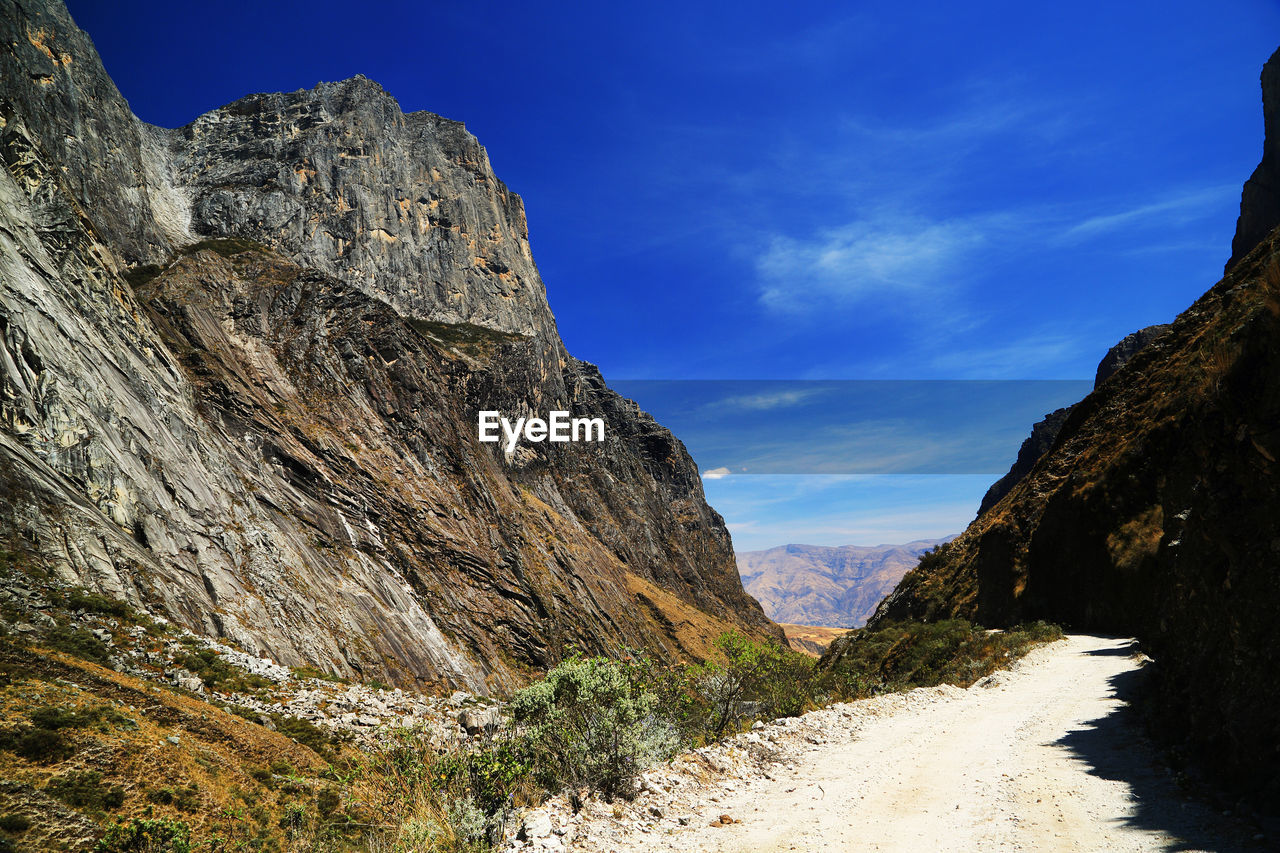 Road amidst mountains against blue sky 