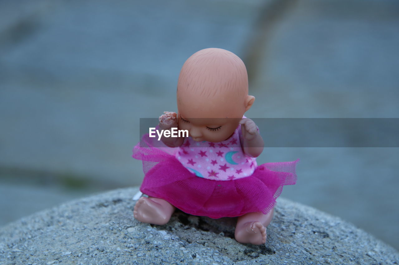 Close-up of cute doll on rock outdoors