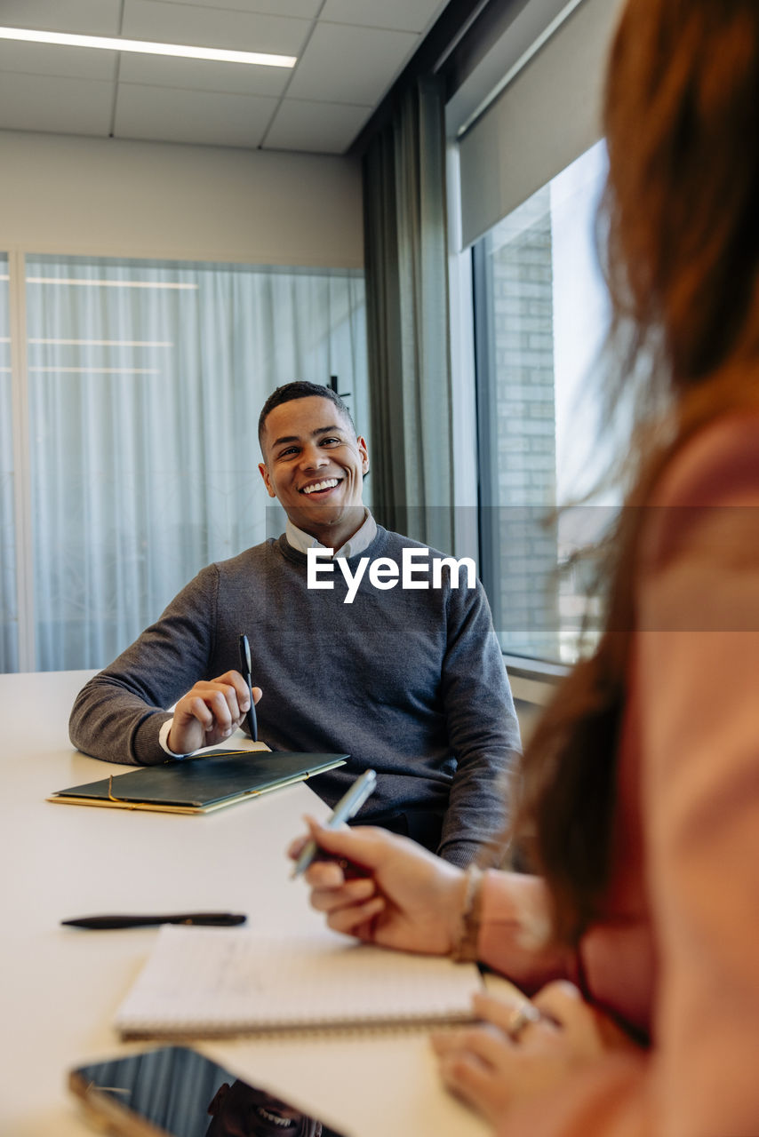 Happy businessman discussing with female colleague in coworking office