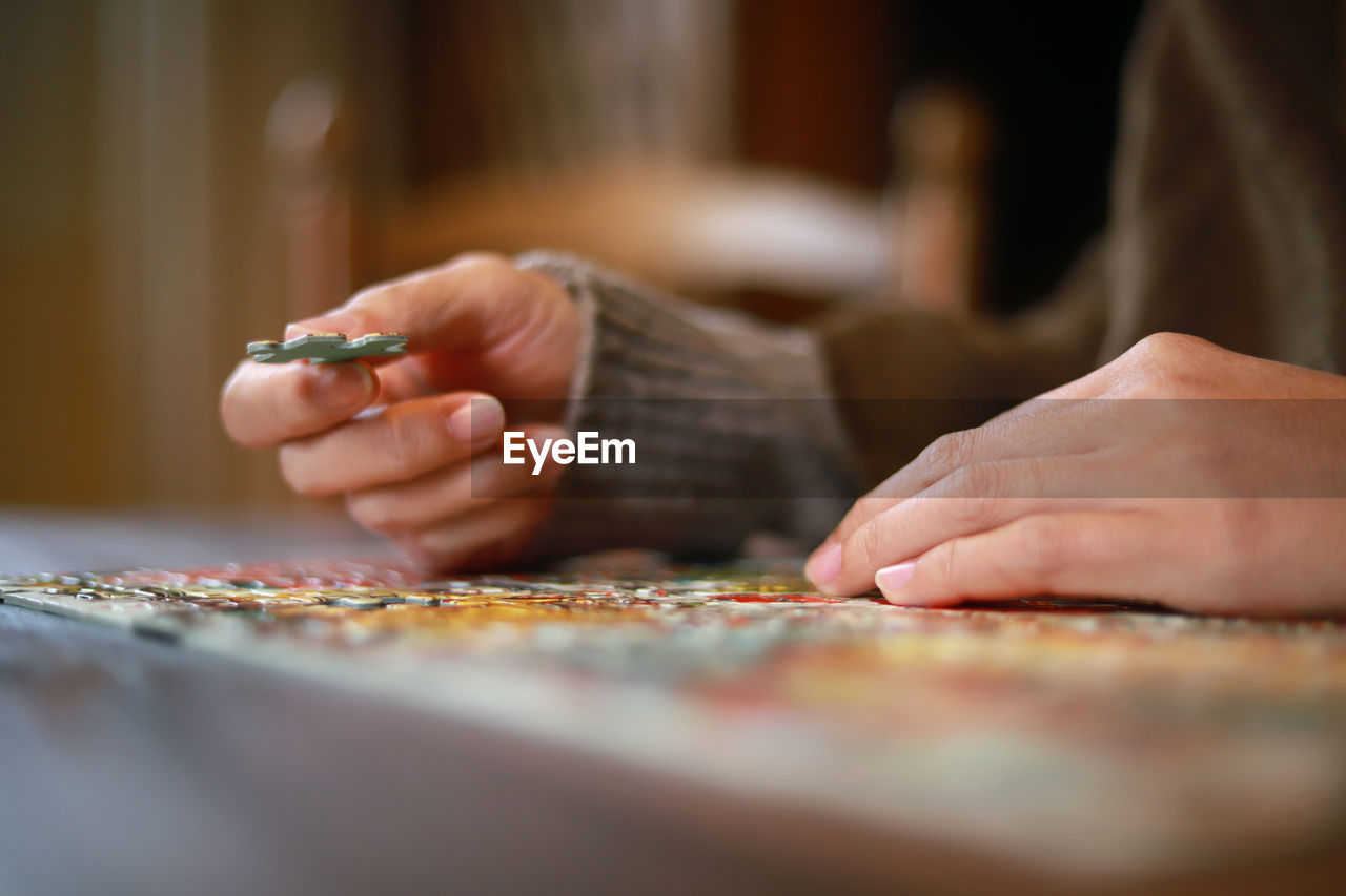 Midsection of woman playing puzzle on table