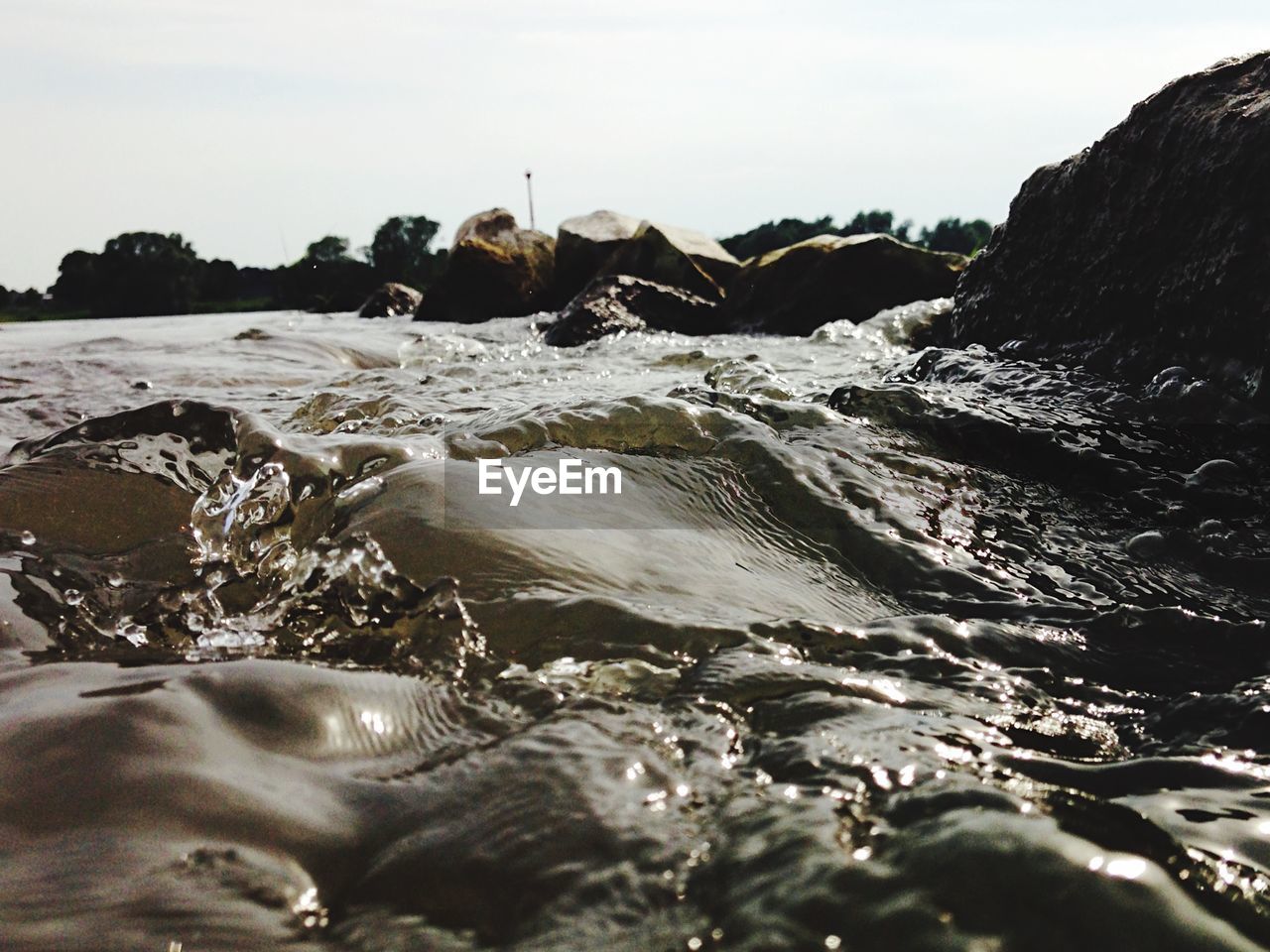 Close-up of water by rock against sky