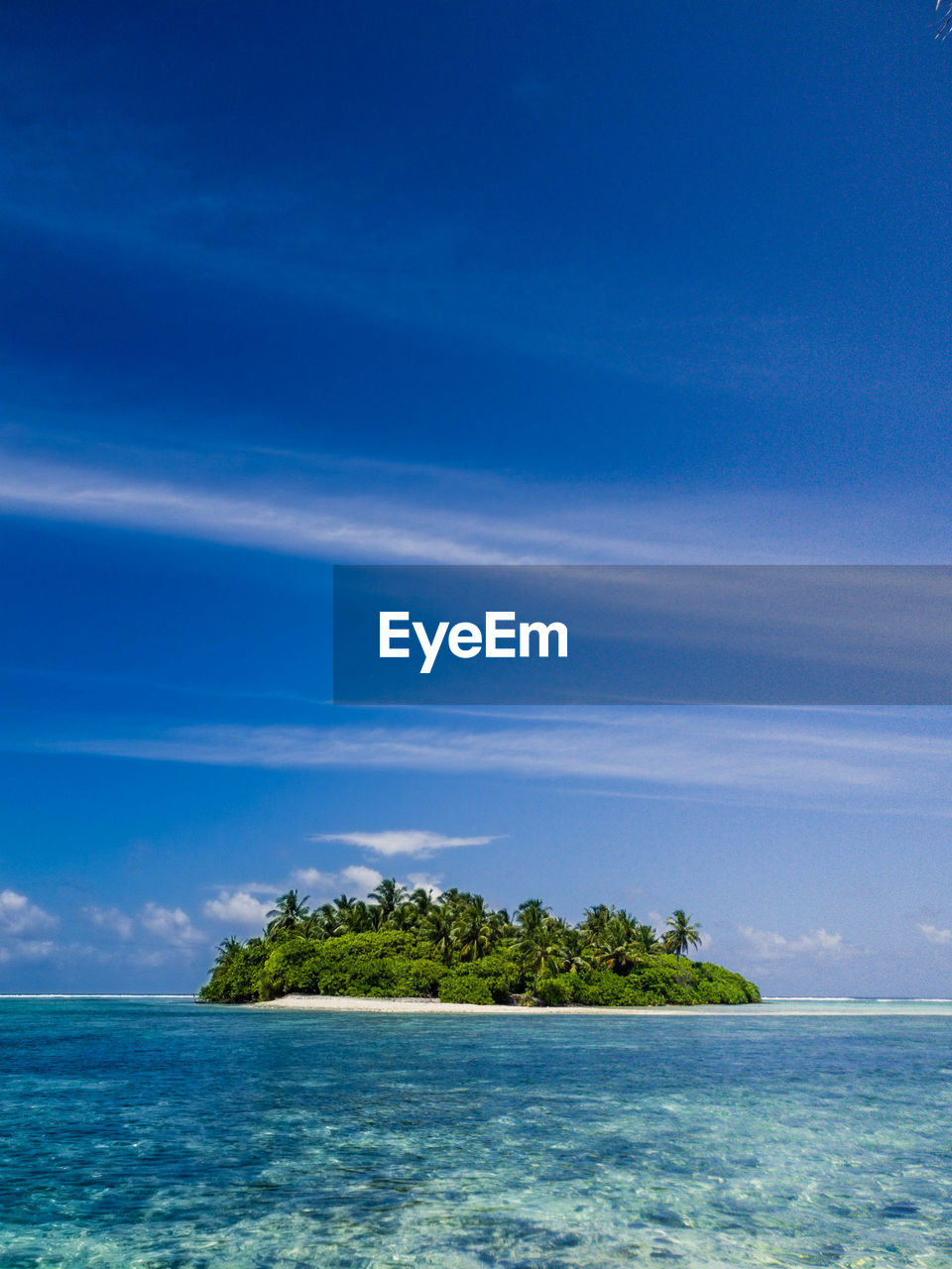 Scenic view of small island with reef against sky