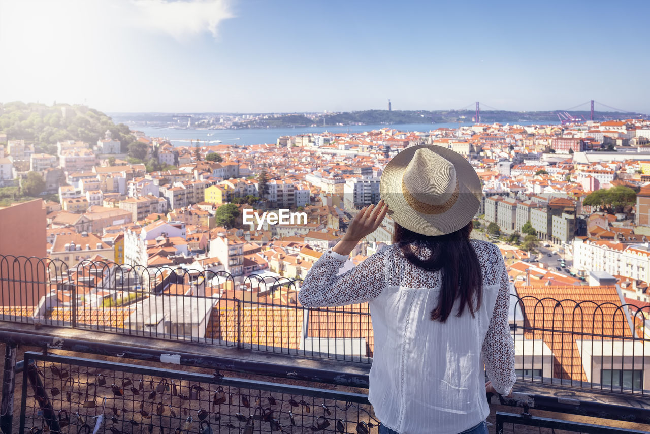 rear view of woman looking at cityscape against sky