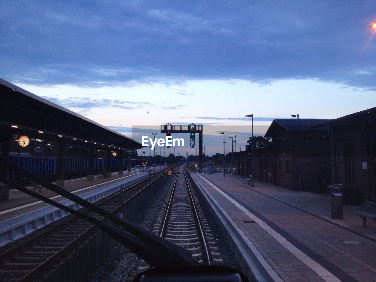 Railroad station against cloudy sky seen through train windshield