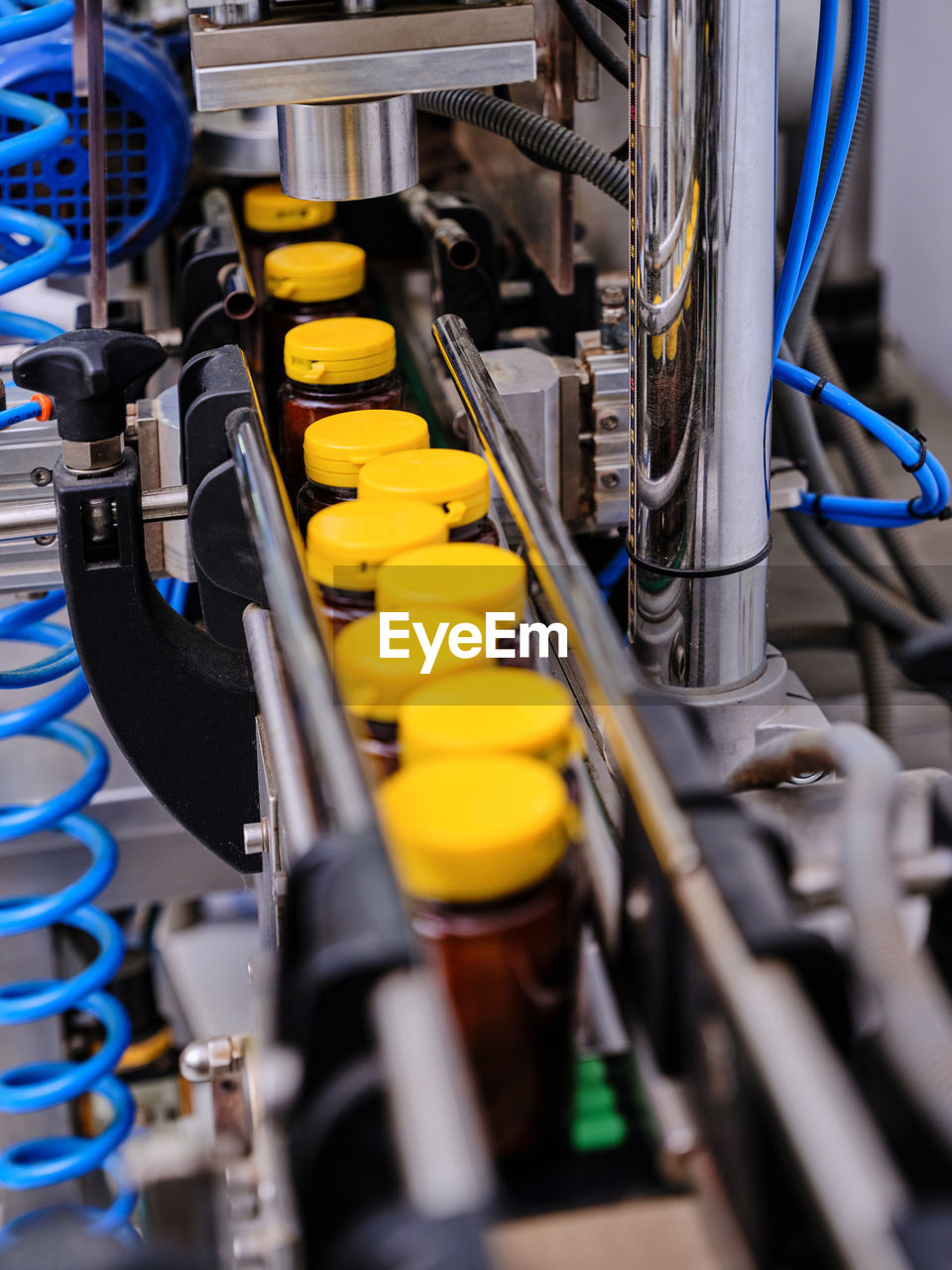 From above of modern pharmaceutical machine capping plastic bottles with liquid medicine on conveyor at factory