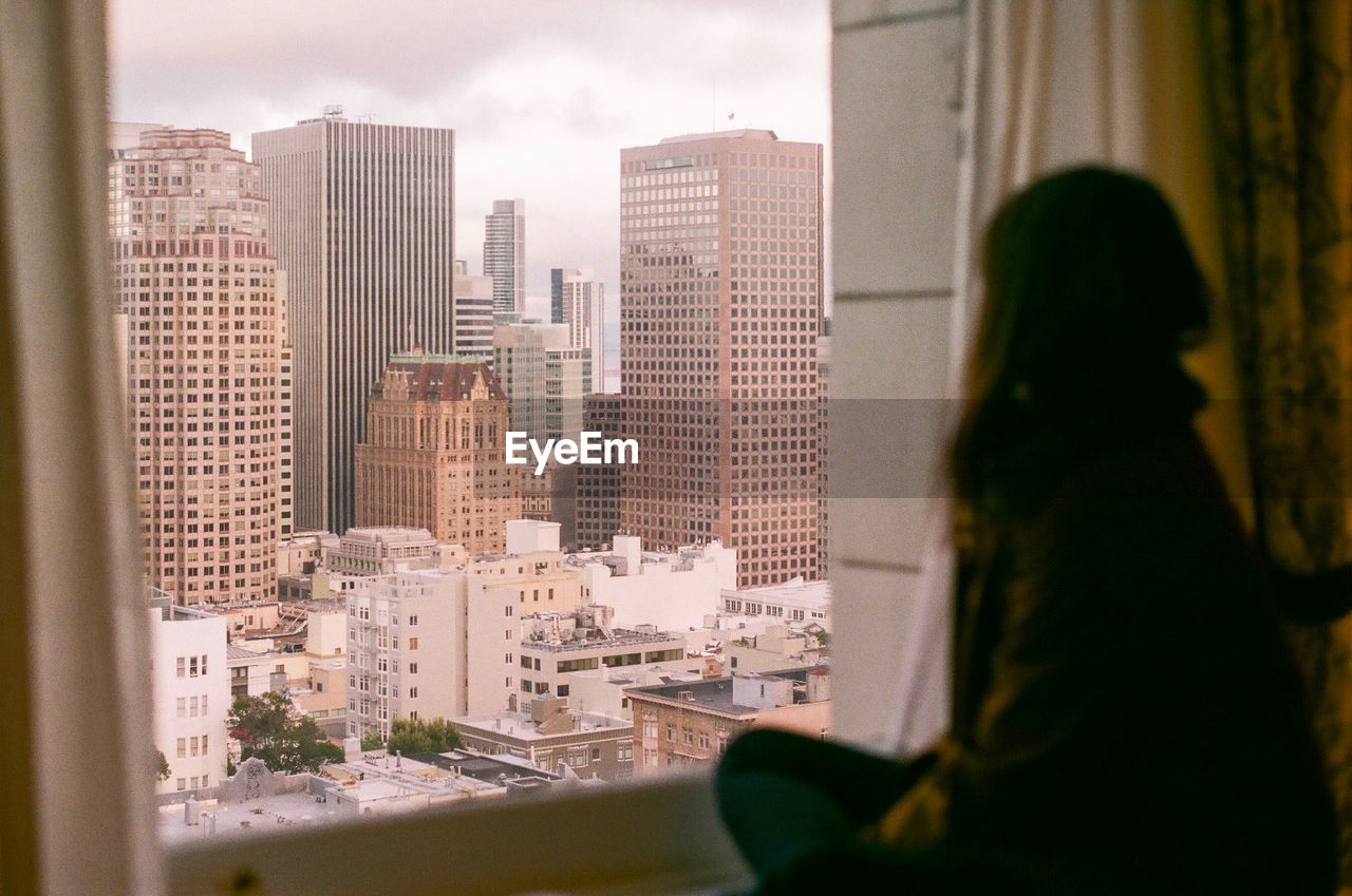 Woman looking at cityscape through window