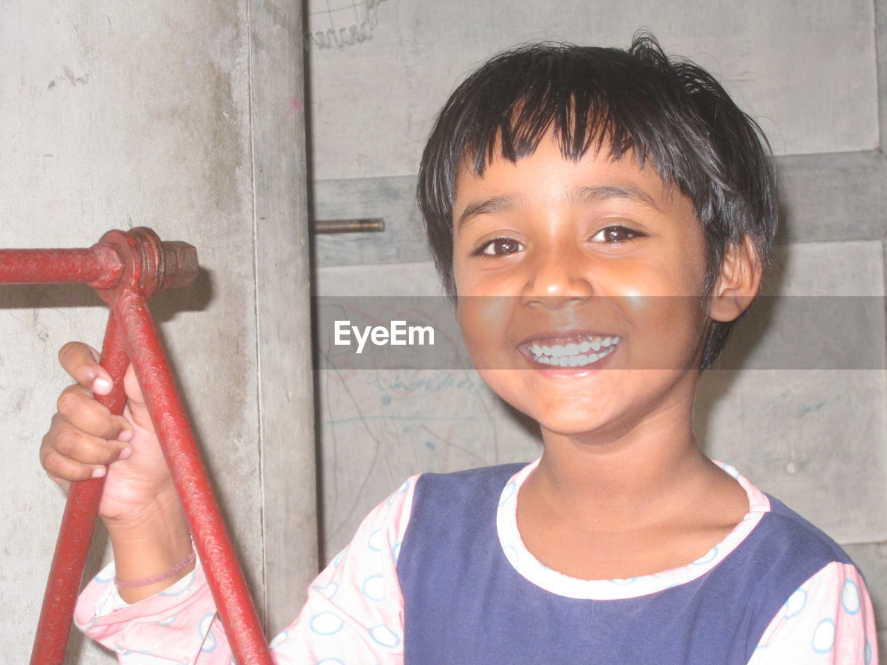 Close-up portrait of smiling girl standing against wall