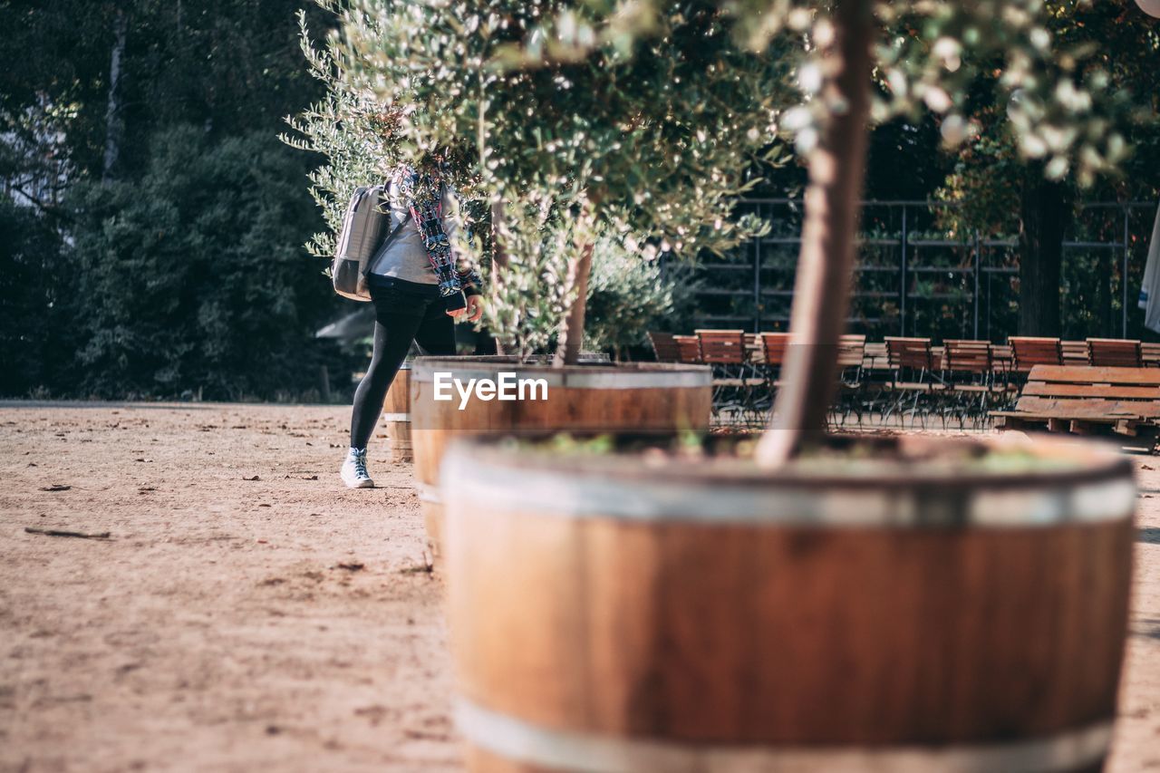 Side view of woman walking amidst potted plants at park