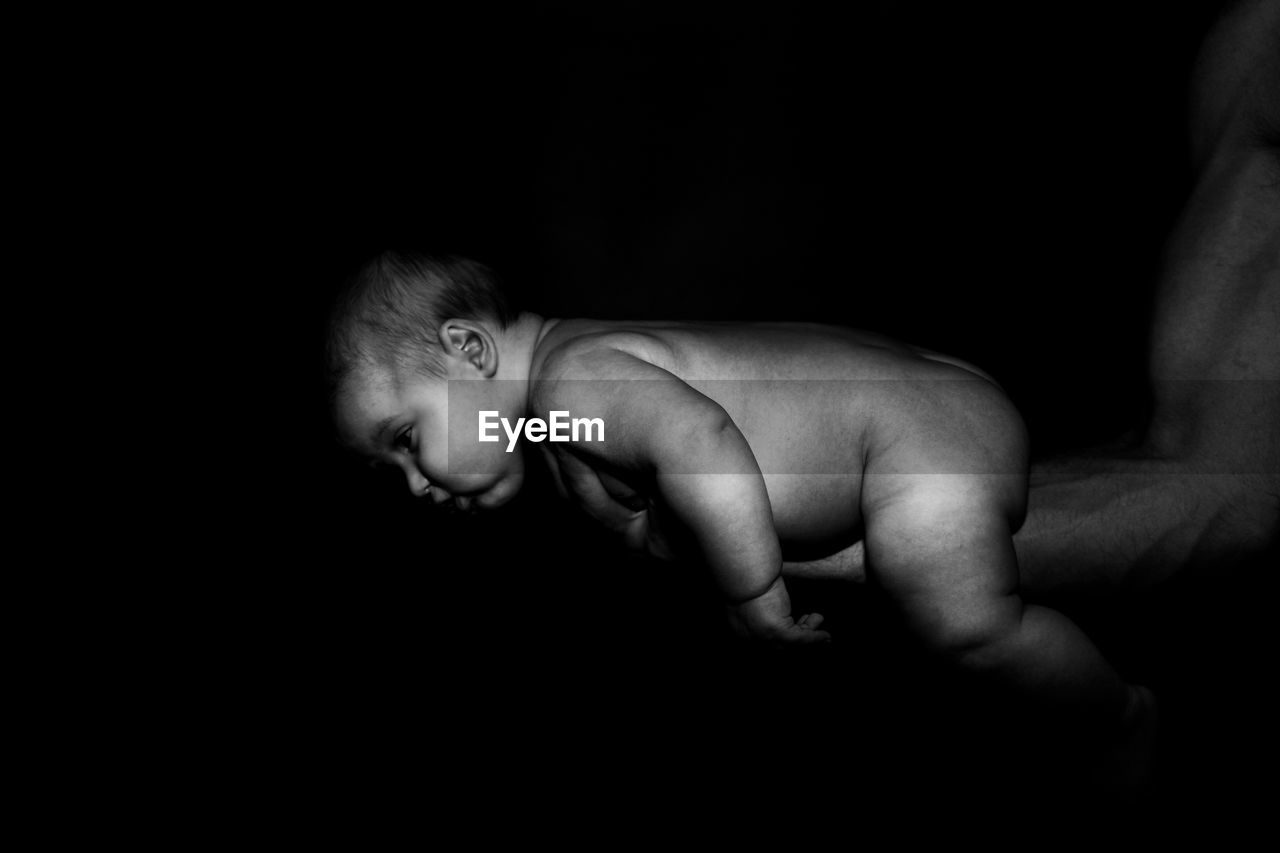 Portrait of shirtless baby boy against black background