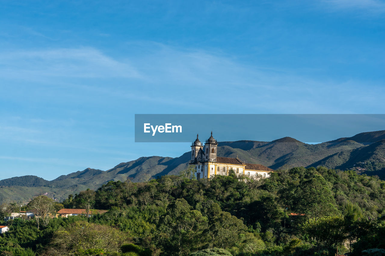 Scenic view of building and mountains against blue sky