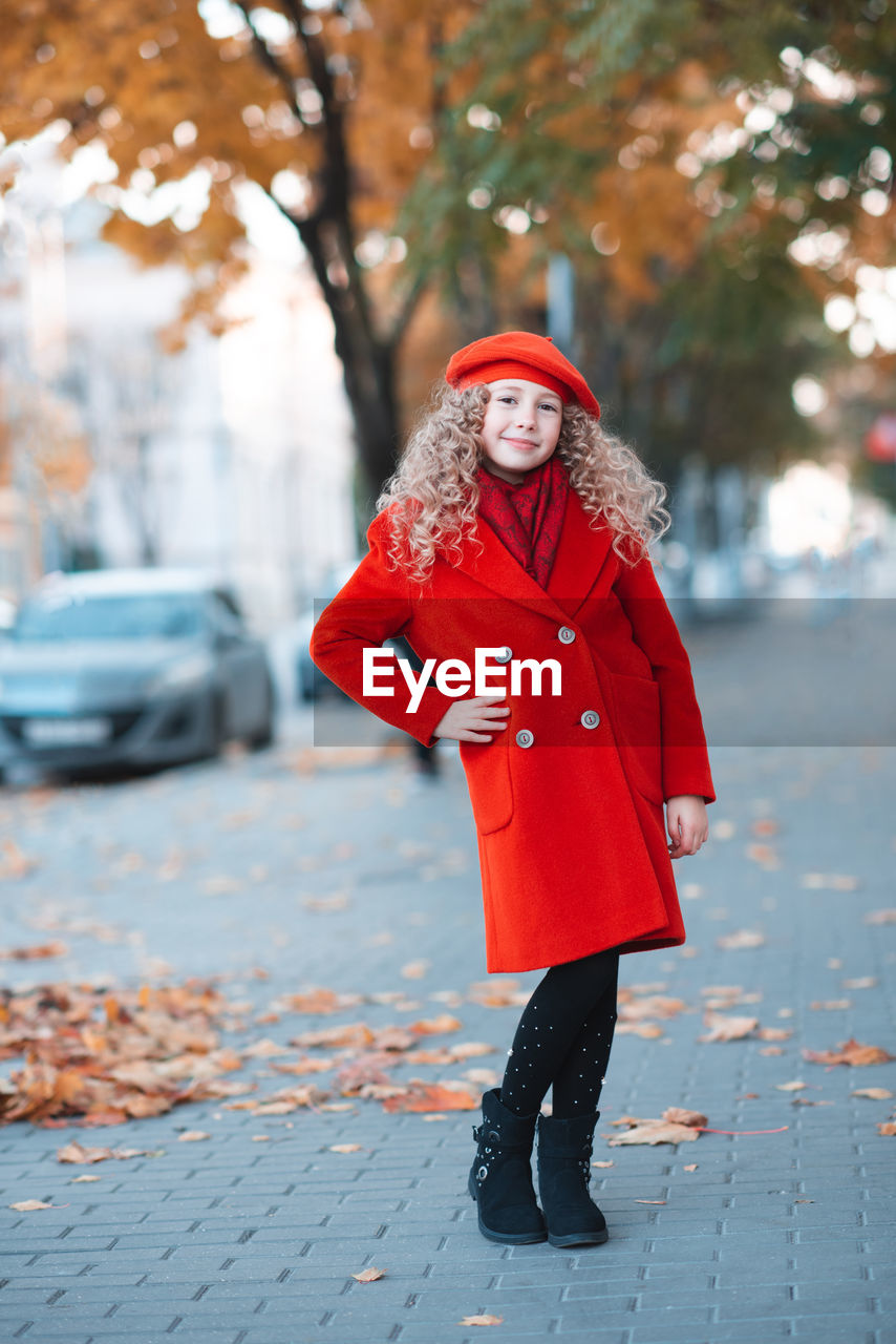 Stylish happy kid girl 5-6 year old with blonde curly hair wear red color jacket and beret hat