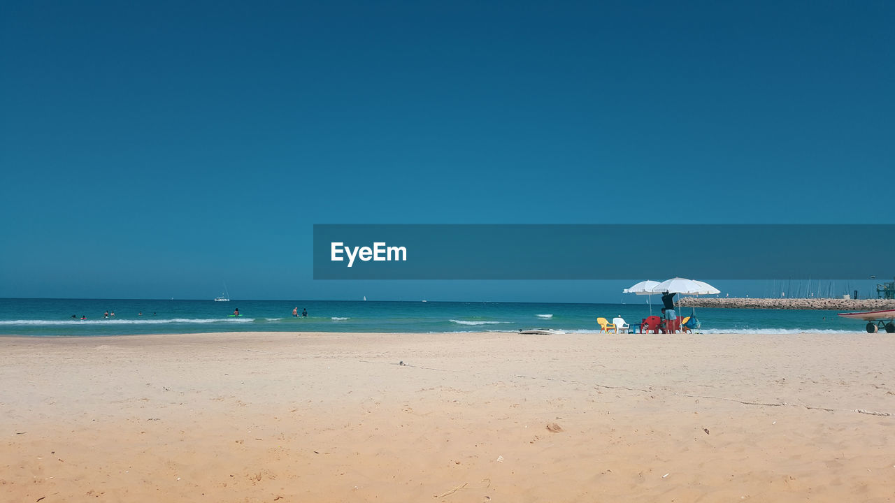 Scenic view of beach against clear blue sky