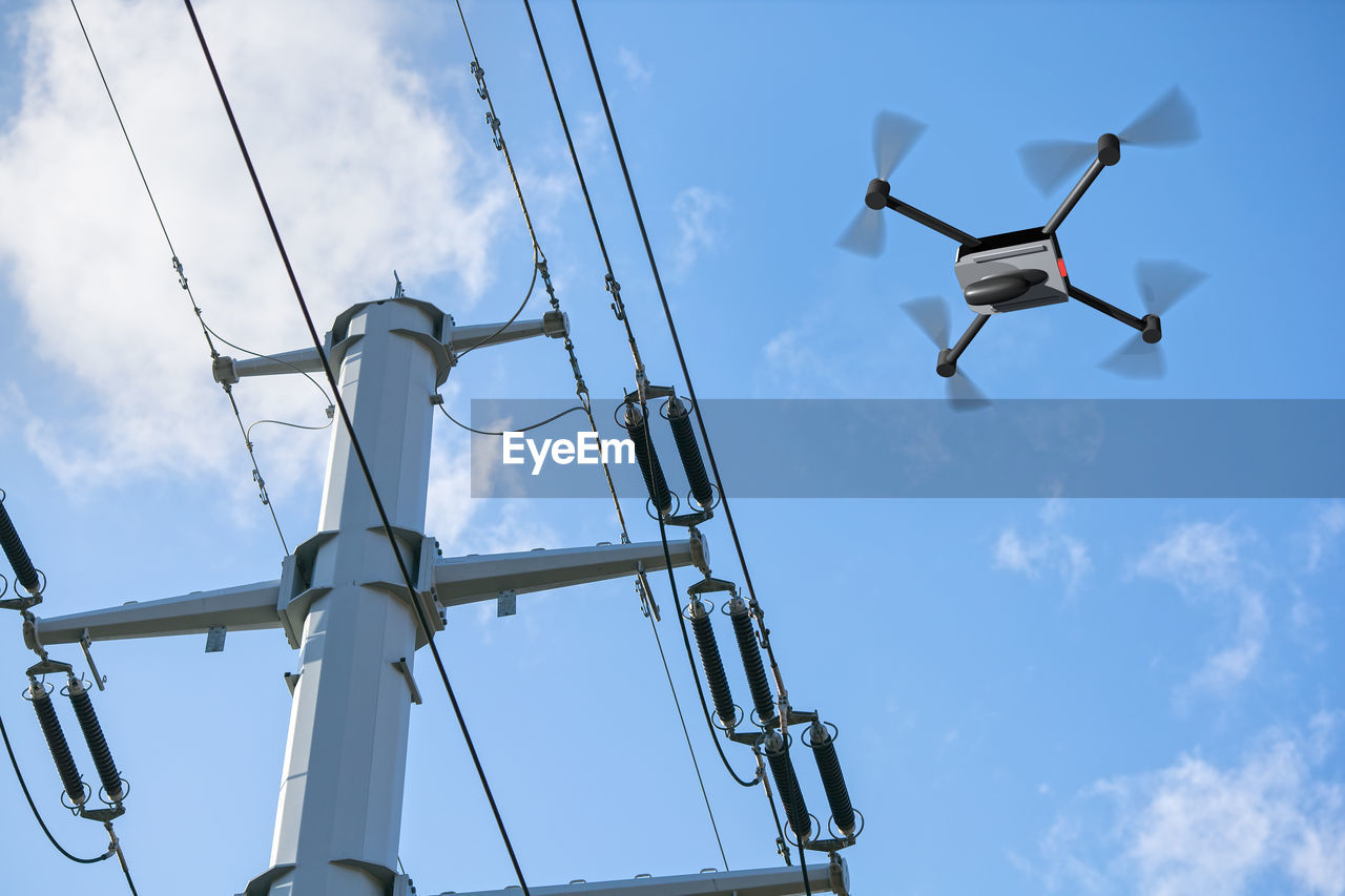 Low angle view of drone flying by electricity pylon against sky