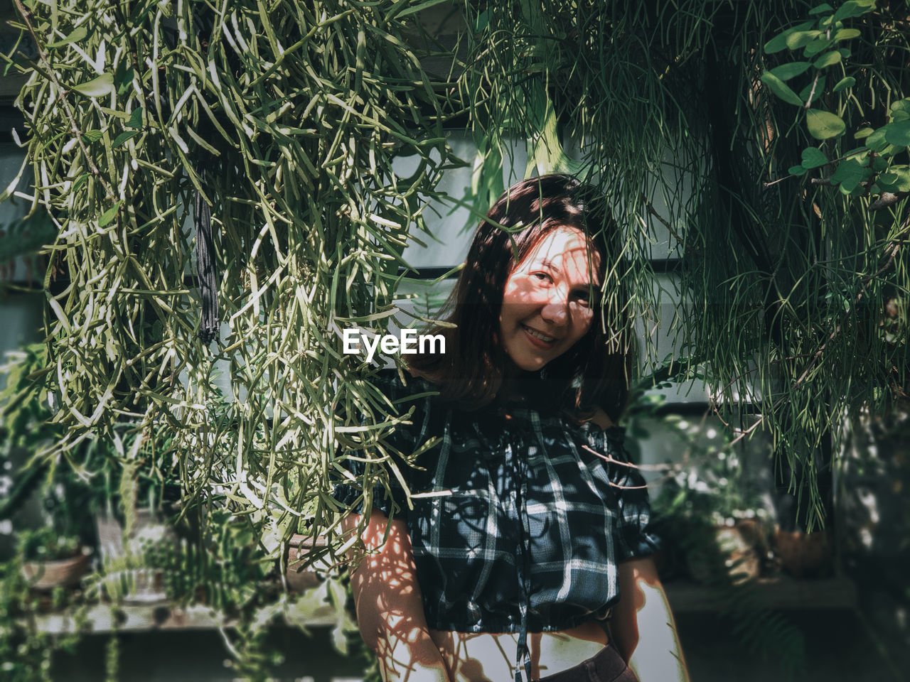 Portrait of smiling woman standing against plants