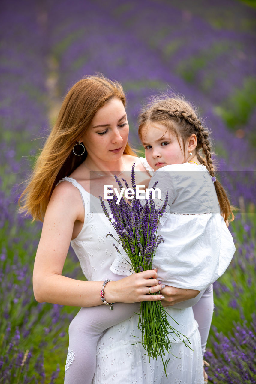 Mother showing flower to girl on field