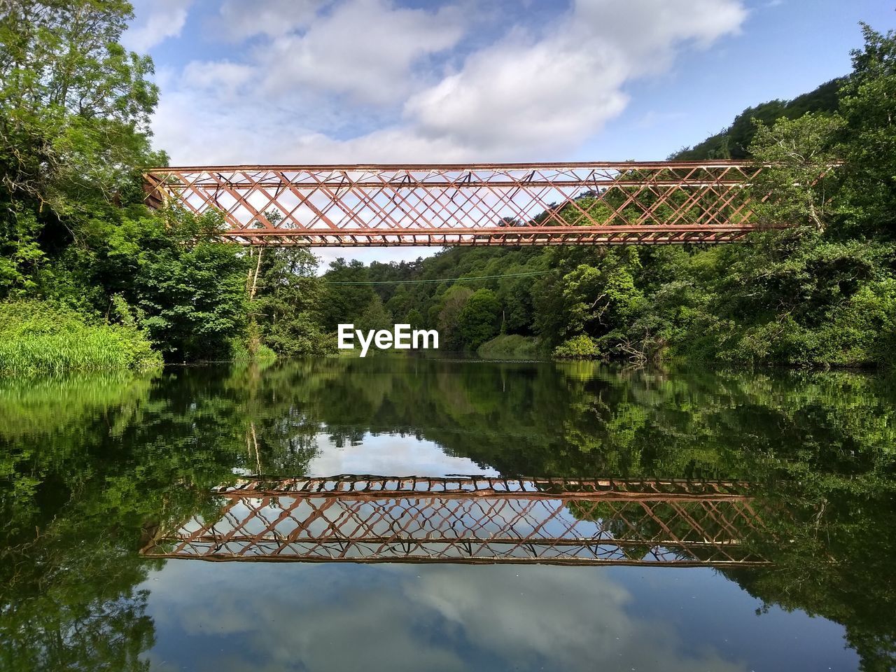 REFLECTION OF BRIDGE ON LAKE AGAINST SKY