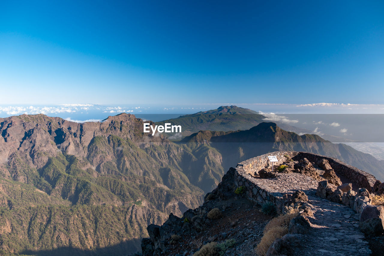 Panoramic view of mountain range against blue sky