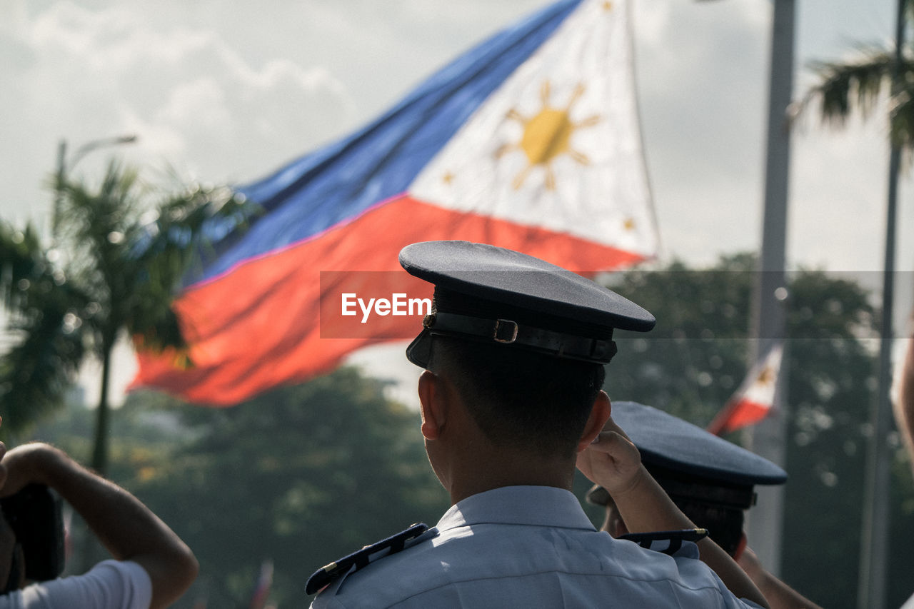 Rear view of police saluting philippines flag