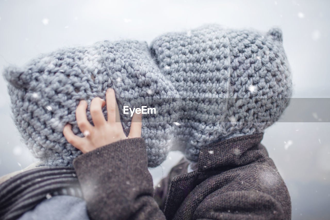 Girl in knitted grey hat hugging her frozen smaller brother