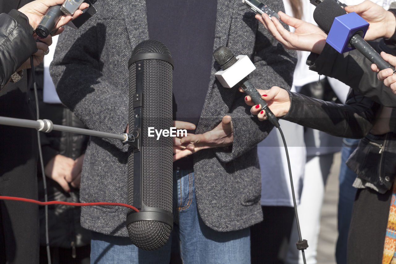 Cropped hands of journalists taking businessman interview