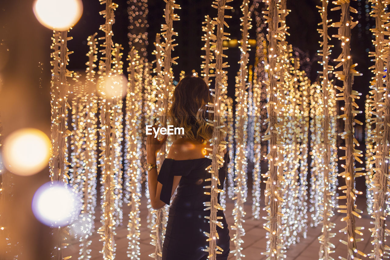 Rear view of woman standing against illuminated lights