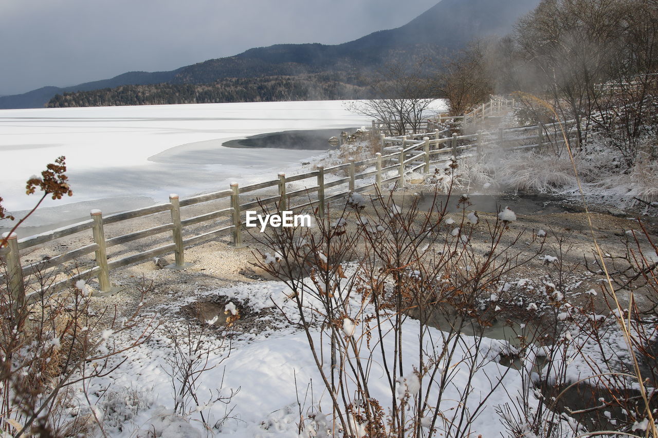 Scenic view of lake by snowcapped mountains against sky