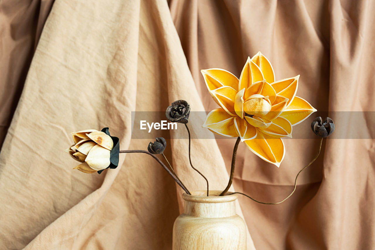 Dried flowers in wooden vase against draper. monochromatic modern still life.
