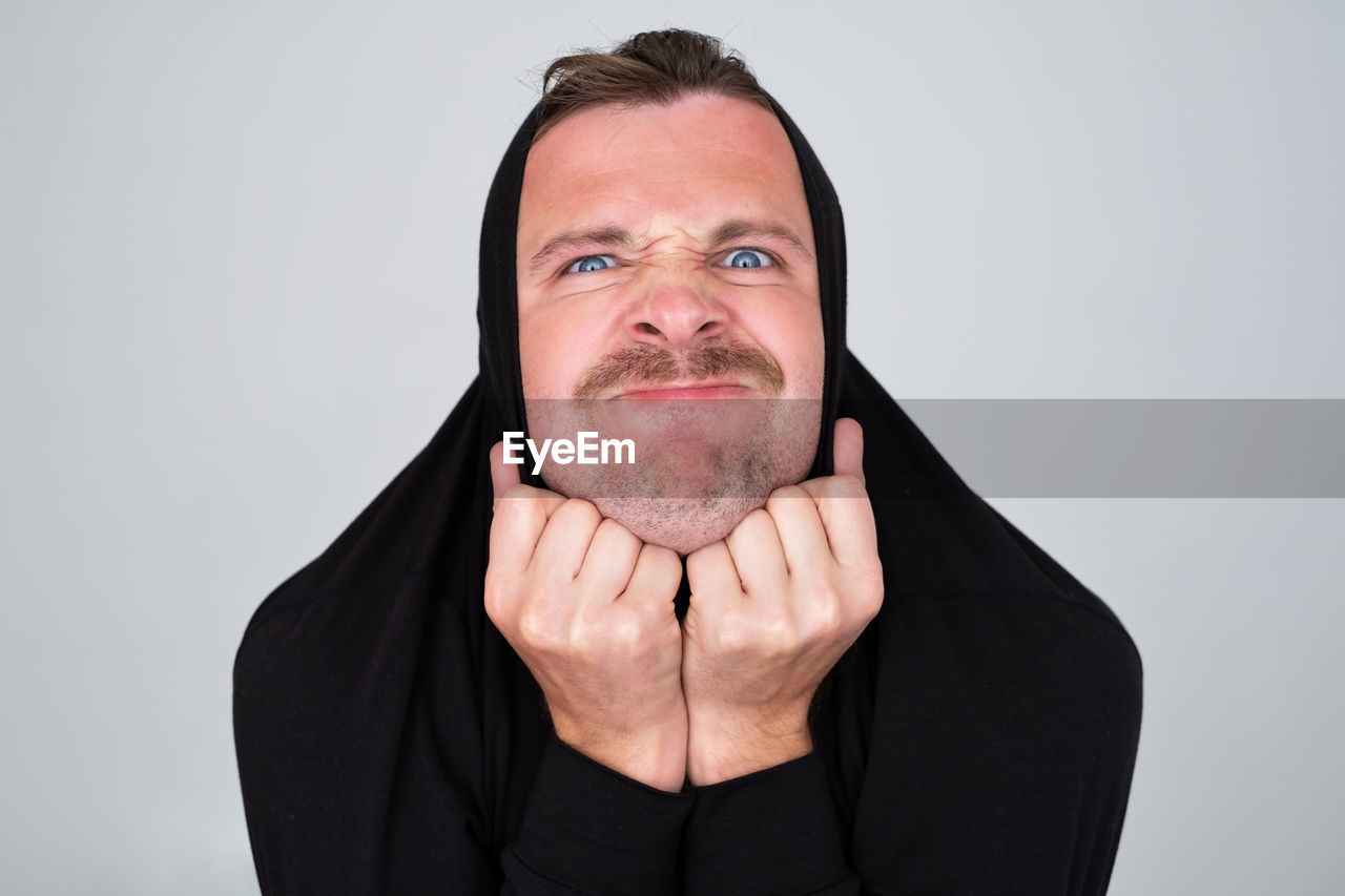portrait, one person, adult, studio shot, human face, men, looking at camera, front view, indoors, person, human head, beard, facial hair, headshot, emotion, gray, nose, mature adult, hand, gray background, finger, moustache, human hair, white background, clothing, human mouth, casual clothing, facial expression