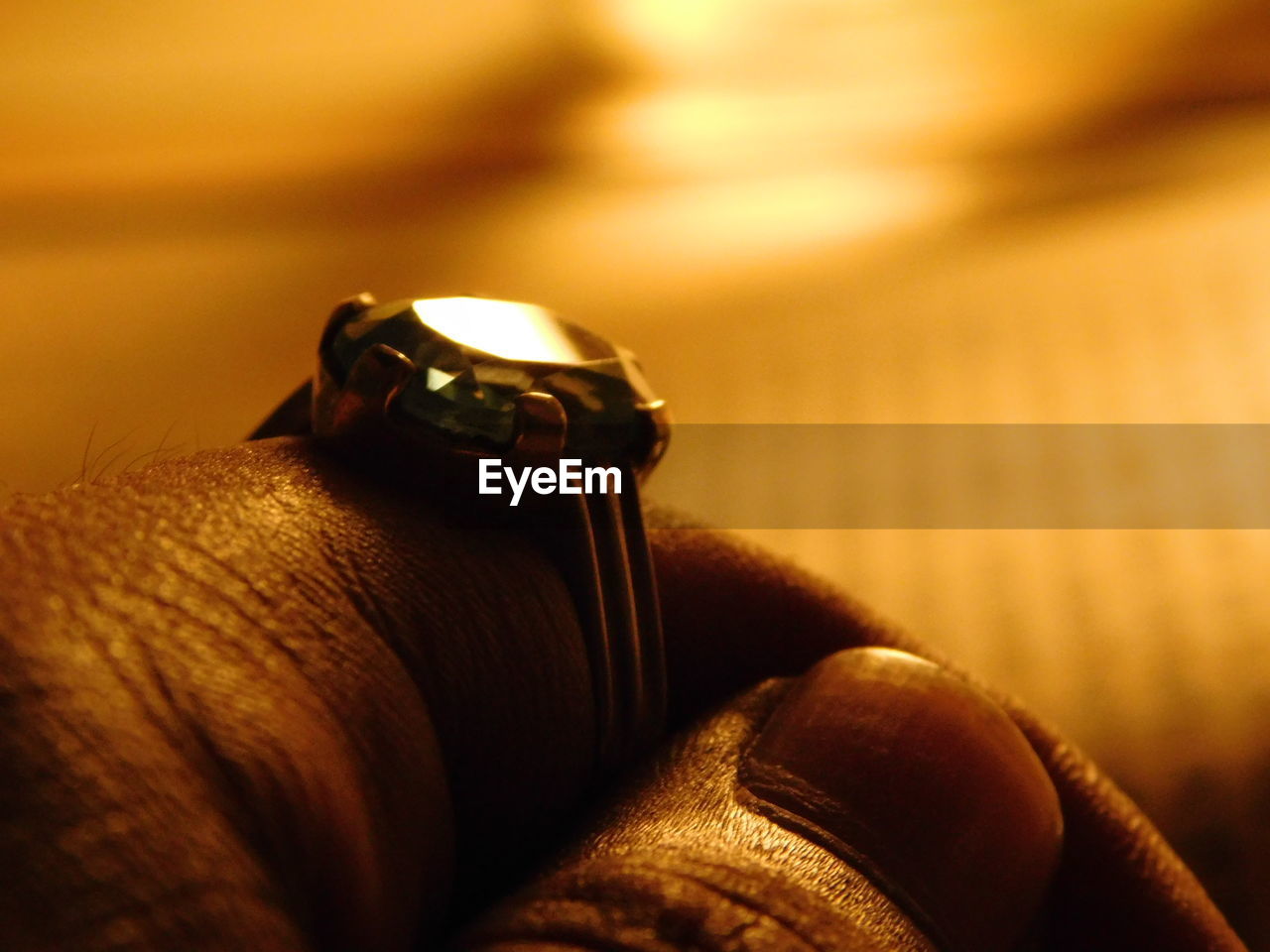 Cropped hand wearing diamond ring in illuminated room