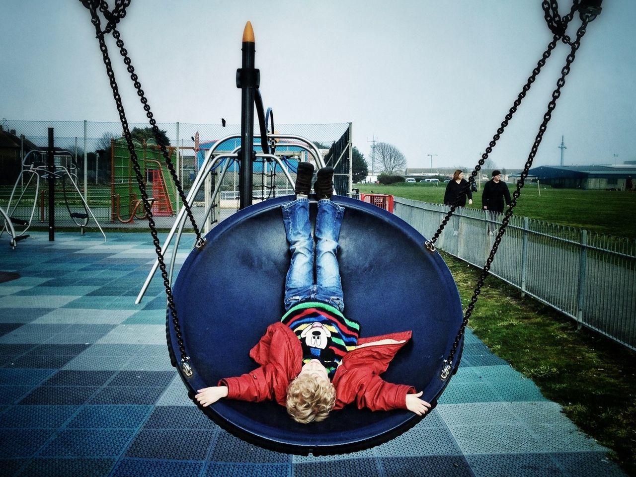 UPSIDE DOWN IMAGE OF GIRL RELAXING ON FOOTPATH AT PARK AGAINST CLEAR SKY