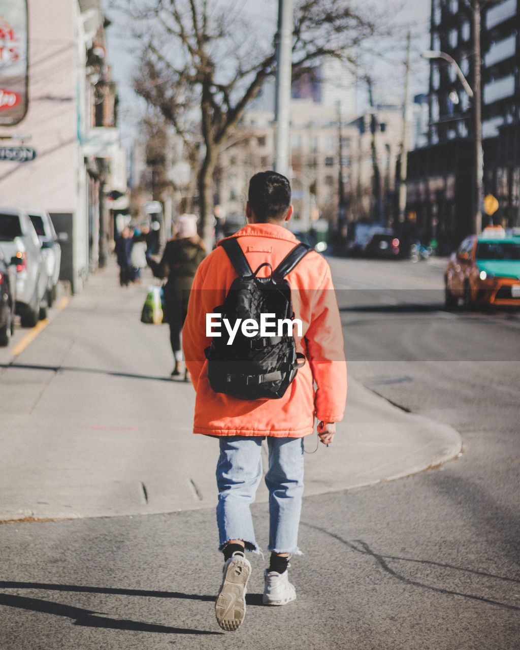 REAR VIEW OF MAN WALKING ON STREET