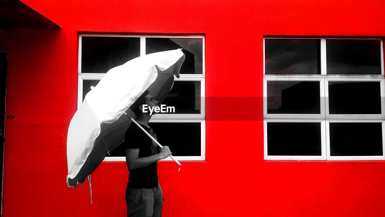 Man holding umbrella in front of red building