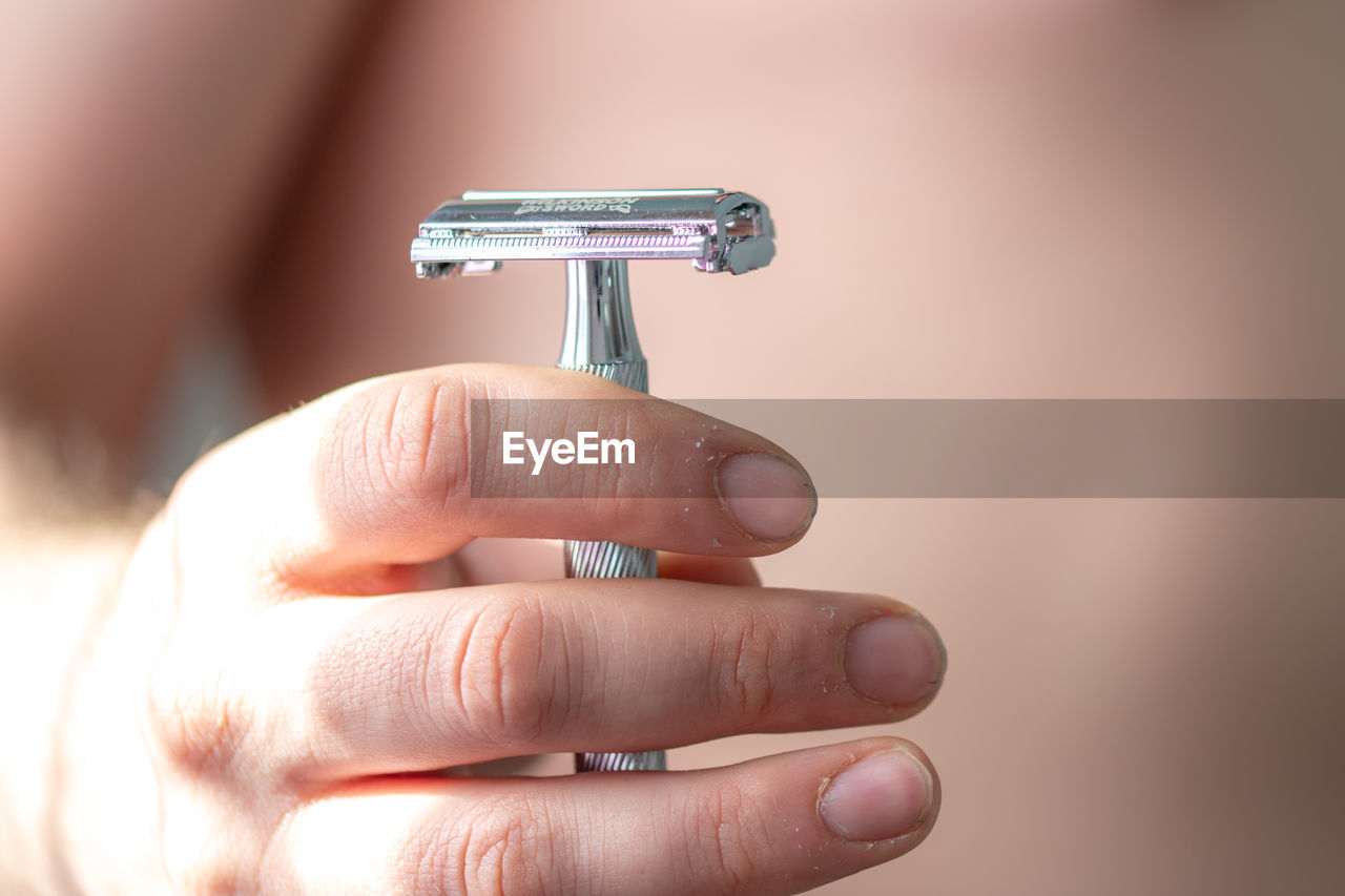 Midsection of shirtless man holding razor