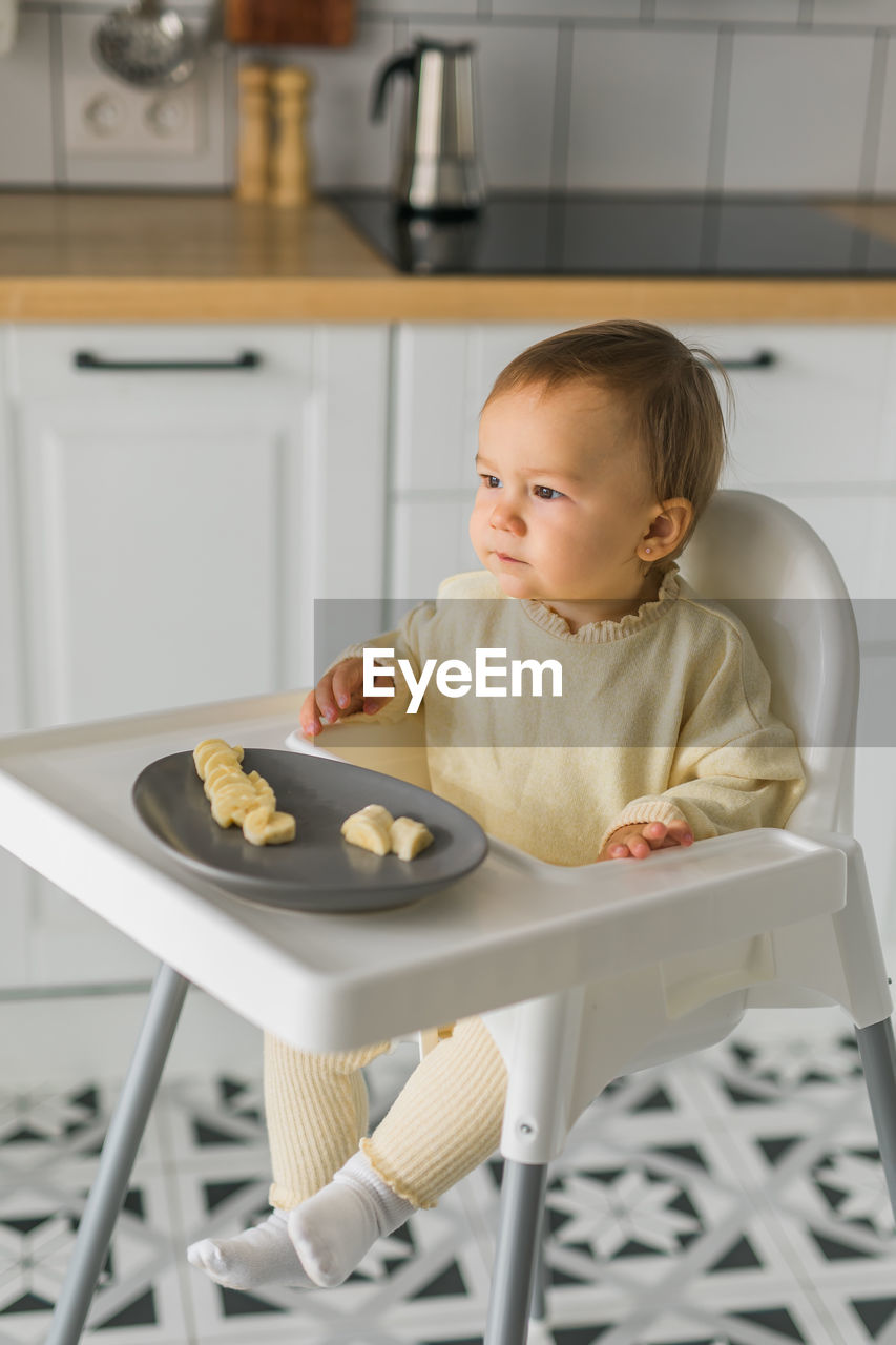 portrait of cute baby boy sitting on table at home